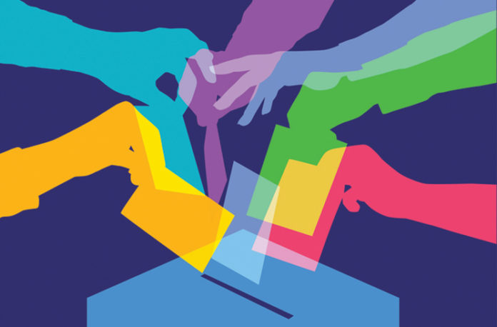 colorful hands putting ballots into a box